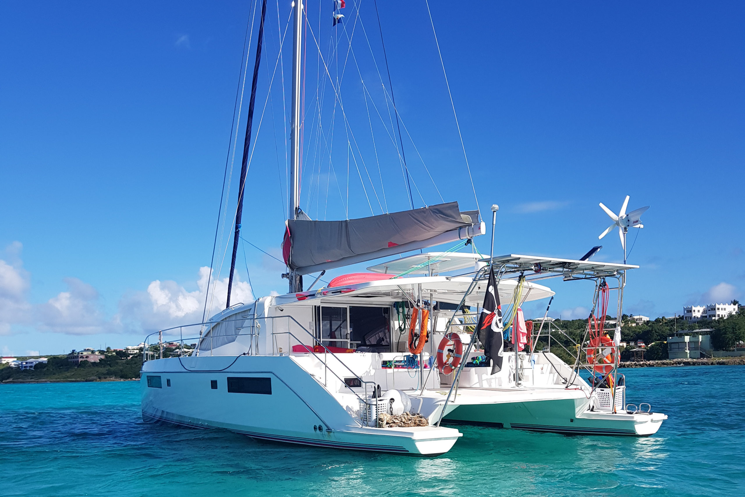 The catamaran "The Good Life" / Backward view from the dinghy on crystal-clear waters
