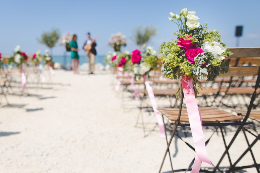 Wedding ceremony on the beach with bouquets on the chairs and musicians