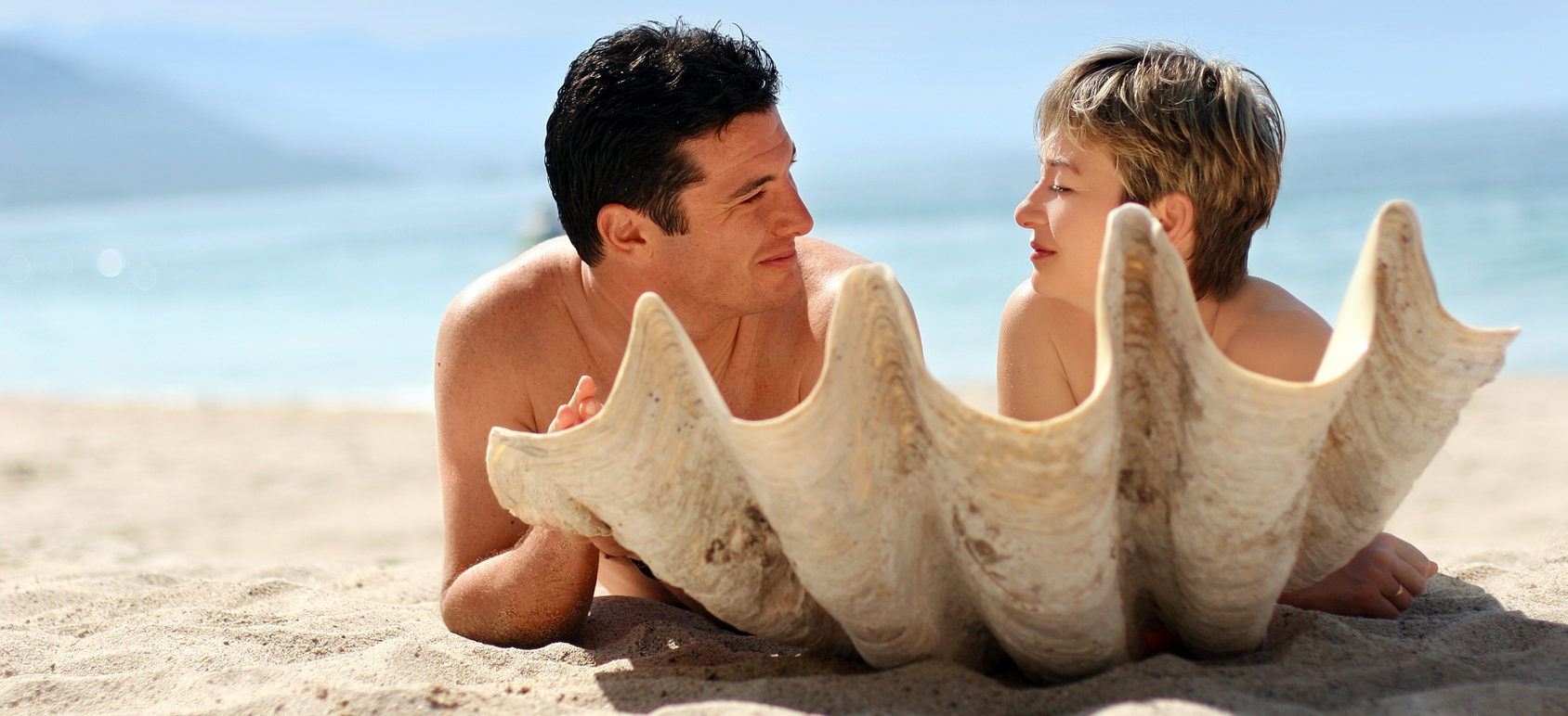 romantic couple on the beach behind the seashell
